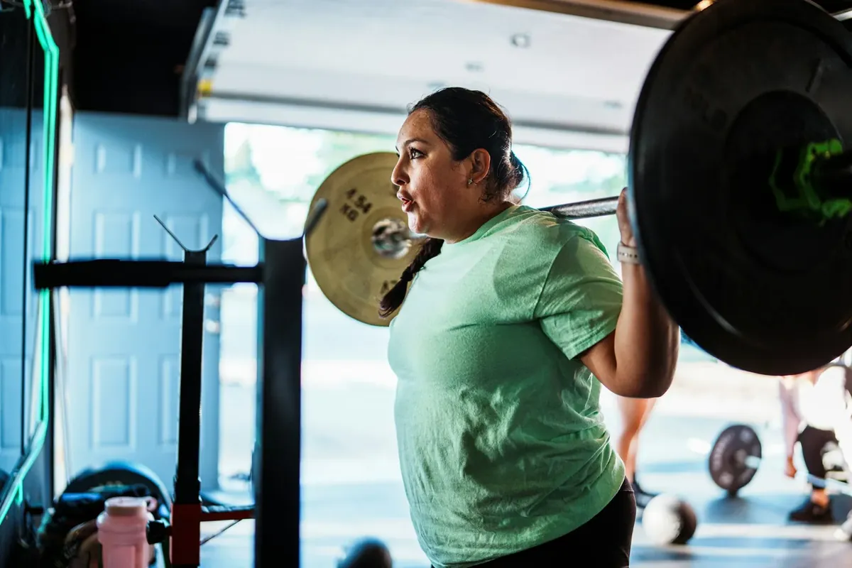 A woman doing a barbell squat with steady form